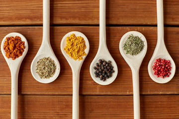 food, culinary and unhealthy eating concept - spoons with different spices on wooden table