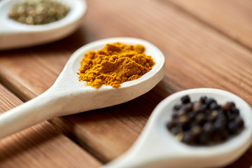 food, culinary and unhealthy eating concept - spoons with different spices on wooden table