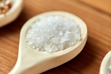 food, culinary and unhealthy eating concept - close up of wooden spoon with sea salt