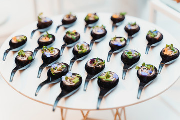 Rolls decorated with petals and herbs, and placed on black spoons