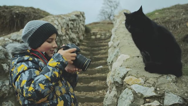 Portrait of a boy who takes a photo of a cat on camera