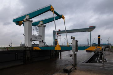 A drawbridge in the city of Finkenwerder on the outskirts of the Hamburg seaport. The steel bridge can be folded up. A day in May with dark rain clouds in the sky.