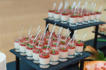 Glasses of panna cotta garnished with strawberry sauce and mint leaves