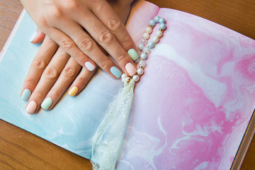 Closeup of cute manicure on female hands on pink and blue background.