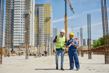 Two engineers on the construction use working equipment.