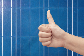 Thumb up on a solar panels background. Photovoltatic power industry.