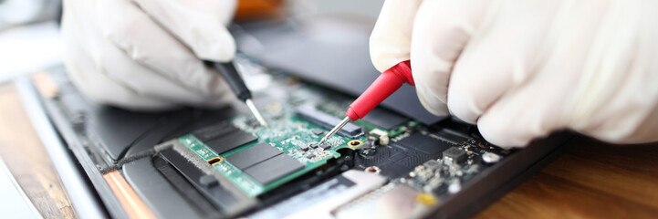 Close-up of circuit board in laptop. Technician soldering microchip using welding machine....