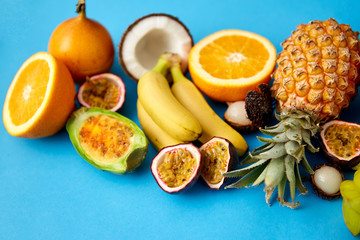 food, summer and healthy eating concept - different exotic fruits on blue background