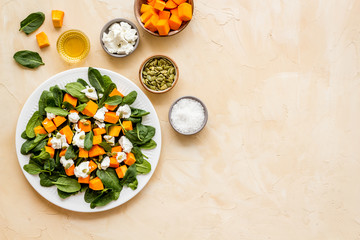 Vegeterian meal concept. Salad with pumpkin and basil on beige background top-down copy space