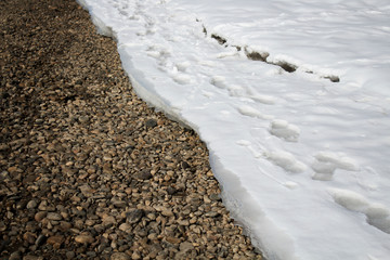 Snow and stones. The bank of river. Nature background.