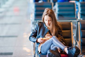 Adorable little girl at airport in big international airport near window