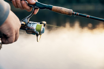Fishing rod with a spinning reel in the hands of a fisherman.