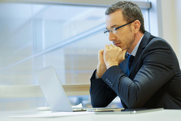 Obraz premium Businessman at work being thoughtful in front of laptop