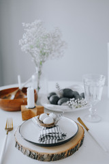 Easter table setting with white plate, gray textile napkin, candles, quail and chicken eggs and blossom branch.Mock up easter card