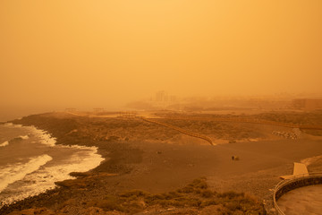 Calima weather with low visibility towards San Blas and Golf del Sur, popular southern resorts in Tenerife, as seen from Playa Grande in the small village of Los Abrigos, Canary Islands, Spain