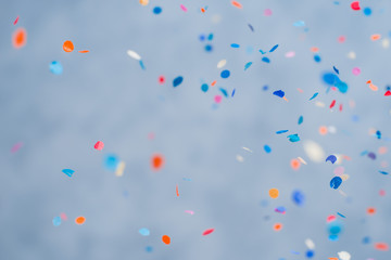 Colorful confetti falling on a holiday on a blue background - obrazy, fototapety, plakaty