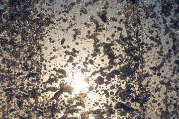 Splashing water fountain against sun and clear sky.