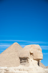 Sunny view of the Great Sphinx of Giza standing tall with the Great Pyramid in the distance in...