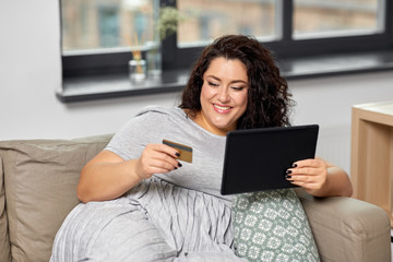 technology, online shopping and people concept - happy smiling woman with tablet pc computer and credit card on sofa at home