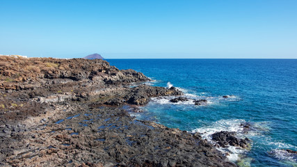 Rough and rocky landscape of the coastal walking path from Montana Amarilla to Amarilla Golf and Golf Del Sur with views of the small fishing villages and Montana Roja, Tenerife, Canary Islands, Spain