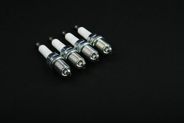 set of 4 spark plugs on a black background with copy space