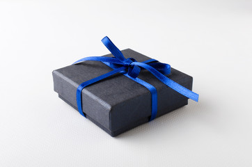 Closeup of wrapped blue gift box with bow on the white background