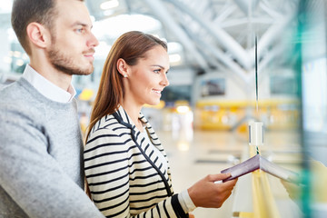 Junges Paar mit Reisepass am Check-In Schalter