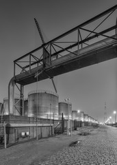Night scene with large silo and pipeline overpass at petrochemical production plant, Port of Antwerp.