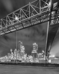 Night scene with illuminated petrochemical production plant and massive pipeline overpass, Antwerp, Belgium.
