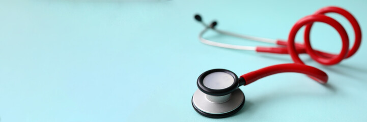 Red doctor stethoscope on blue modern background close-up. Medical insurance concept