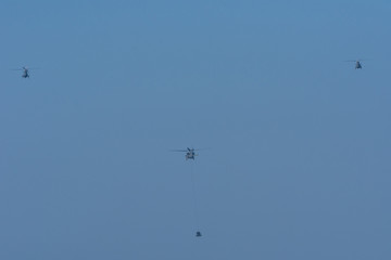 Three helicopters rescue a military team in conflict with people on a rope attached to chopper in the smoke and haze in the MIddle East conflict.