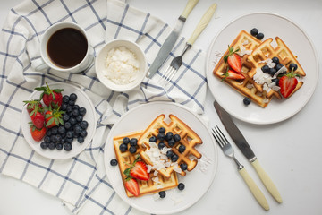 Beautiful breakfast: Viennese Belgian waffles decorated with berries, a plate with strawberries and blueberries