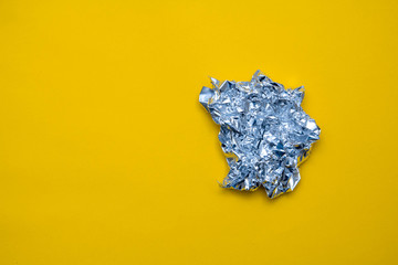 Silver foil on yellow background. Top view. Copy, empty space for text