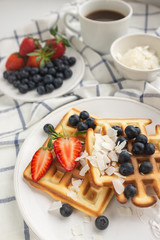 Beautiful breakfast: Viennese Belgian waffles decorated with berries, a plate with strawberries and blueberries