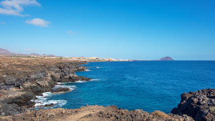 Fototapeta na wymiar Rough and rocky landscape of the coastal walking path from Montana Amarilla to Amarilla Golf and Golf Del Sur with views of the small fishing villages and Montana Roja, Tenerife, Canary Islands, Spain
