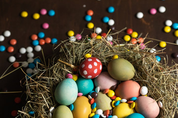 Fototapeta na wymiar Colorful Easter eggs and chocolate candies in the nest
