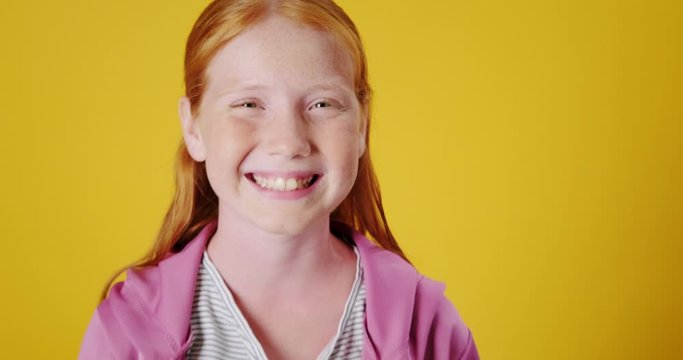 Dolly Out Slow Motion Portrait of Pretty Happy and Smiling Red Hair Teen Crossing her Arms While Smiling Positively showing her teeth. Outgoing Social Young Caucasian Female With Confident Demeanor