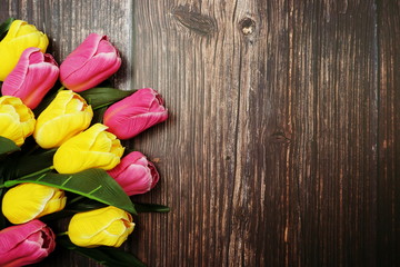 Bouquet of pink and yellow tulips flowers with space copy on wooden background