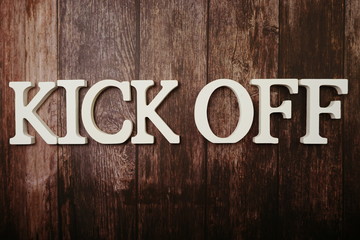 Kick Off alphabet letters on wooden background