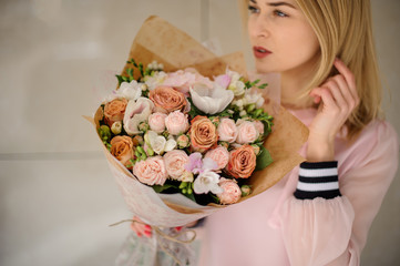 Young blond woman with a bouquet of flowers in pastel colors.