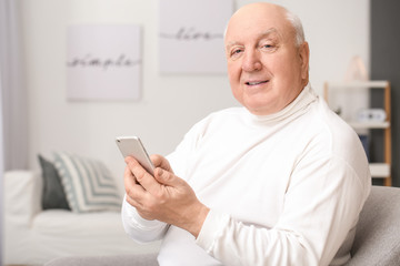 Portrait of elderly man with mobile phone at home