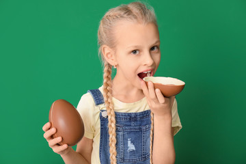 Cute little girl with sweet chocolate egg on color background