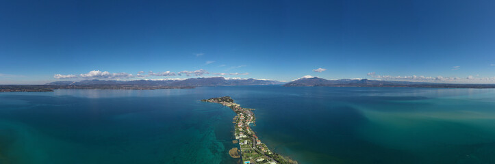 Fototapeta na wymiar Sirmione town, Lake Garda, Italy. Aerial view of Sirmione high altitude. In the background mountains in the snow and blue sky. Aerial panorama