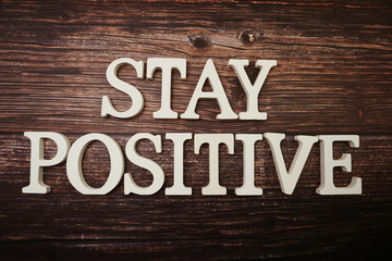 Fototapeta premium Stay Positive alphabet letter on wooden background