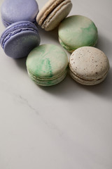 close up view of assorted delicious green, violet and yellow french macaroons on grey background