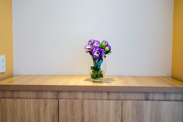 Flower in a glass vase on wooden table in hotel room