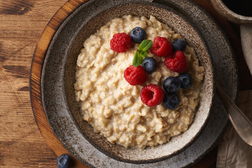 Oatmeal rustic porridge with blueberry, raspberries in ceramic vintage bowl, dash diet with berries