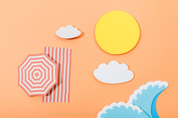 Top view of paper cut summer beach with umbrella and blanket on orange background