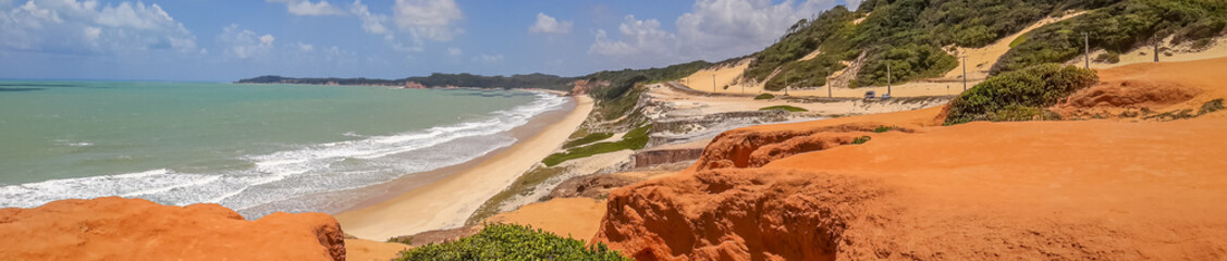 Fototapeta na wymiar Wide angle panorama of brazilian beach with dunes bathed by ocean waves, Pipa, Natal, Brazil. . Concept: holidays in exotic places, Brazilian beaches