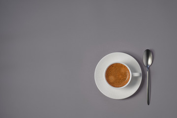 White cup of coffee, spoon on  gray background, flat lay